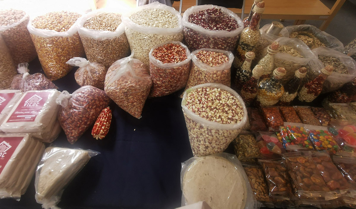 A vendor's display of diverse varieties of maize, alongside other treats.